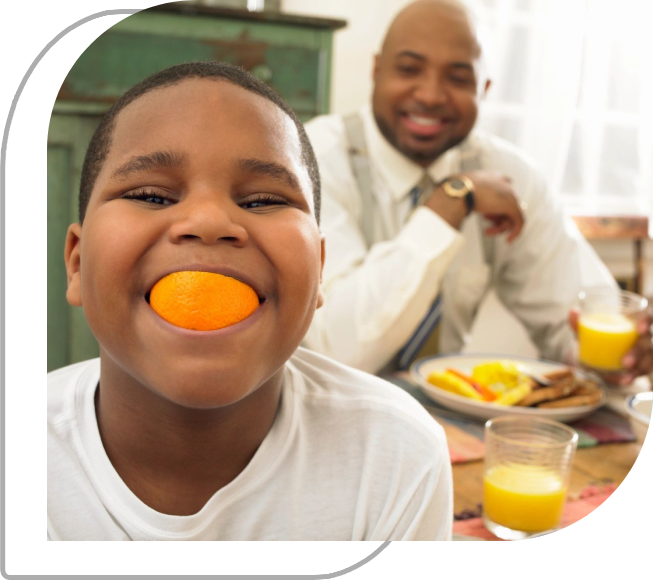 A man and boy eating orange slices at breakfast.