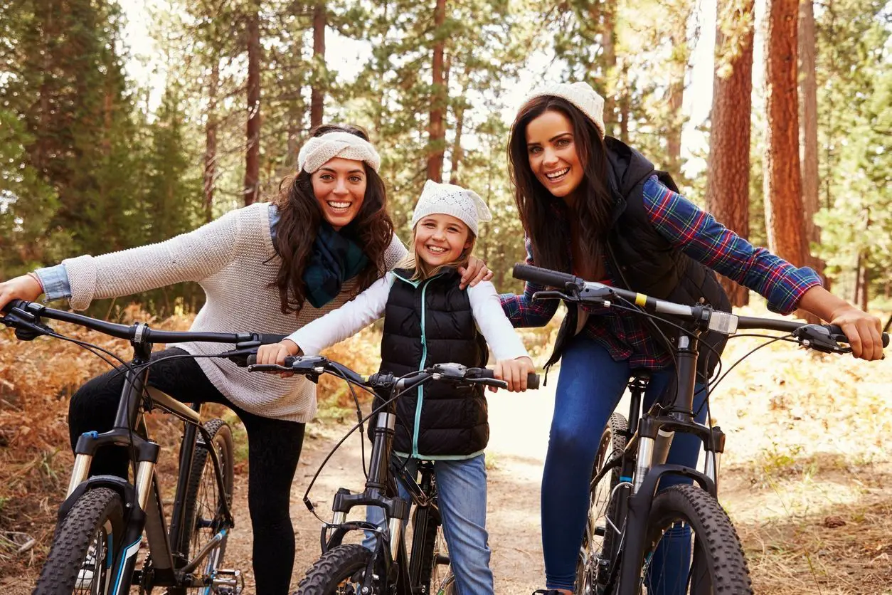 Three women are riding bikes in the woods.